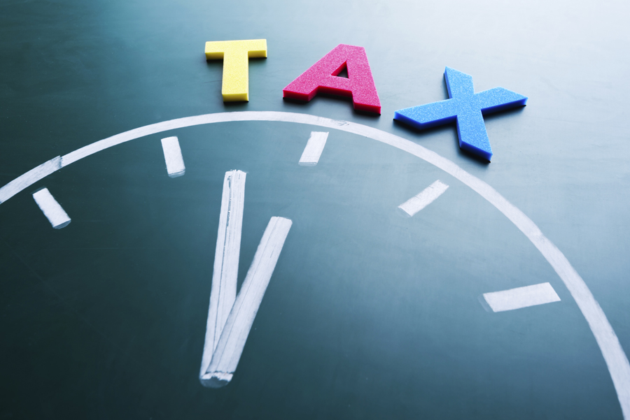 Top half of a clock drawn on a chalkboard with the word 'TAX' written above it.