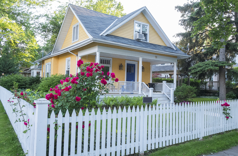 Yellow house with white fence