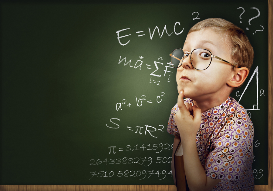 Boy standing in front of chalkboard with a finger on his chin