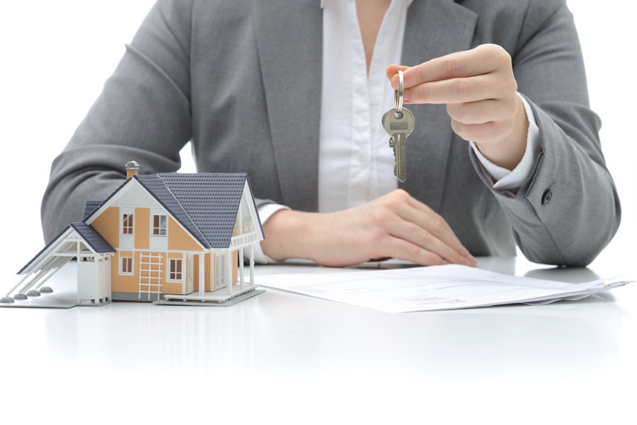 Woman until holding up key by model of house