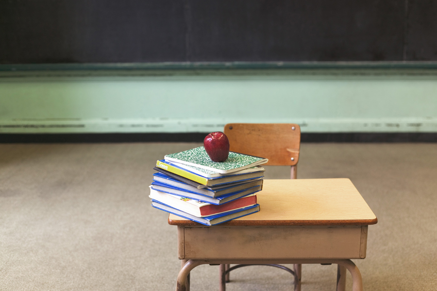 Student desk with books and apple on it