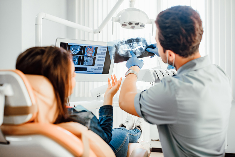 Dentist with patient examining x-rays