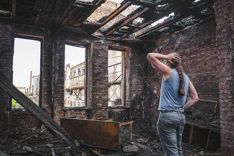 woman looking at home after disaster