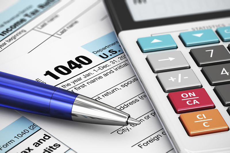 Calculator and pen on top of 1040 tax forms