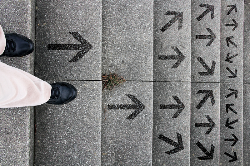 Person walking down steps with arrows going different directions