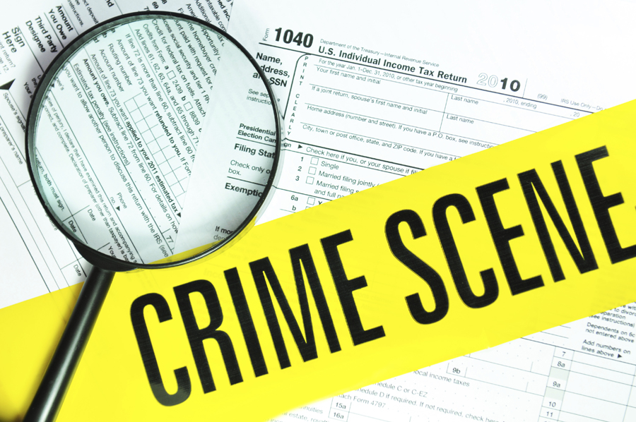 Magnifying glass over tax forms with crime scene tape