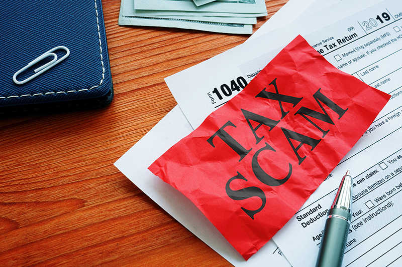 Tax Scam written on red paper over tax return