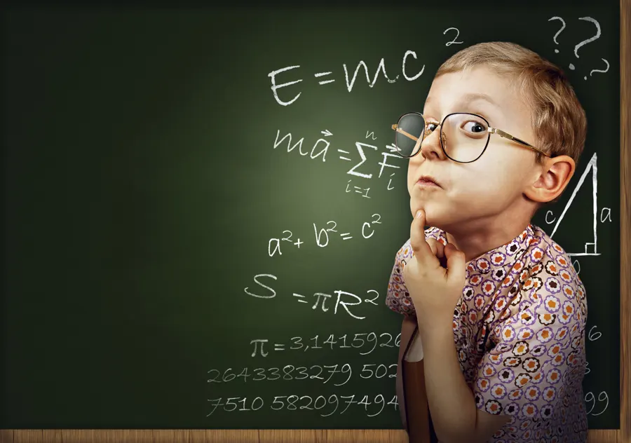Boy standing in front of chalkboard with a finger on his chin
