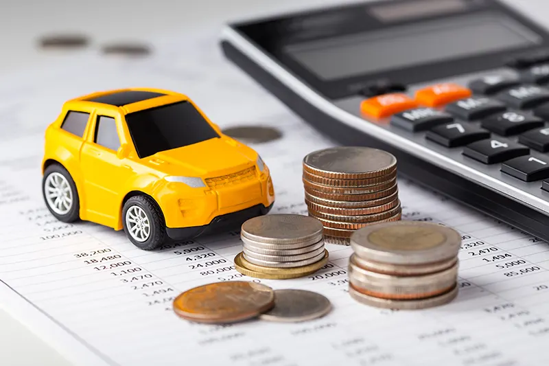 Car, coins, and calculator on a financial document 