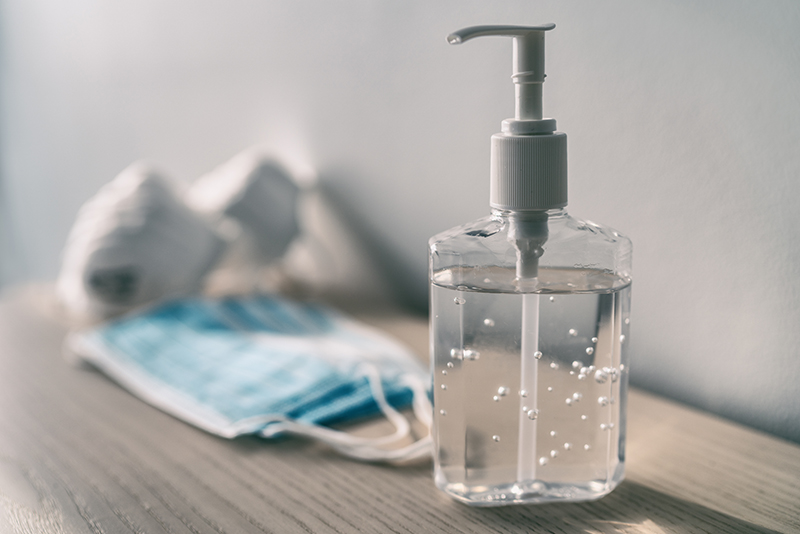 Hand Sanitizer on table with masks in background