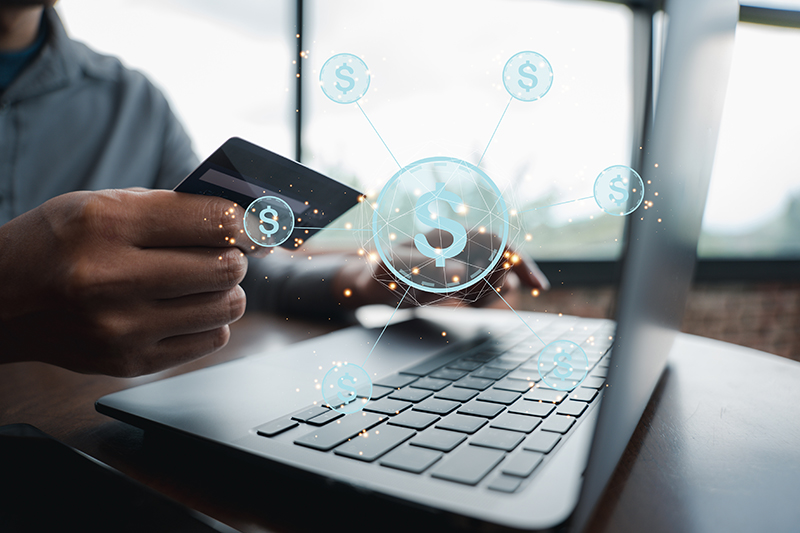 Man holding a credit card near computer with money symbols